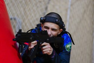 Боец LASERWAR целится из-за красного укрытия.